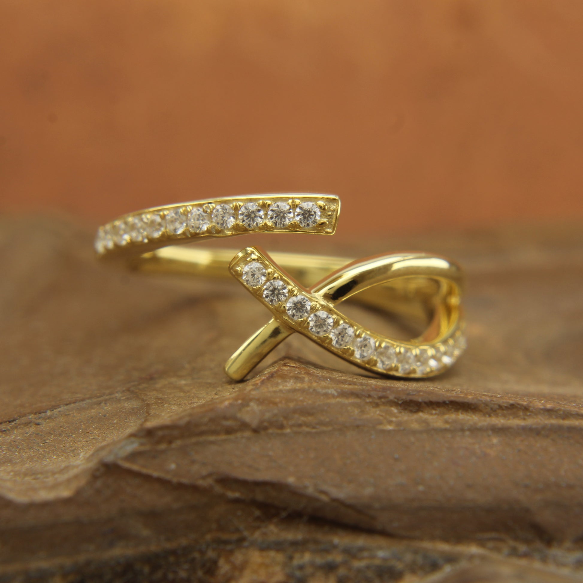 Close-up of handmade diamond crossover ring in recycled gold, Side view of natural diamond ring with micropavé setting,
