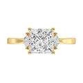 Gold ring with a large central princess diamond and smaller diamonds on the sides on a white background